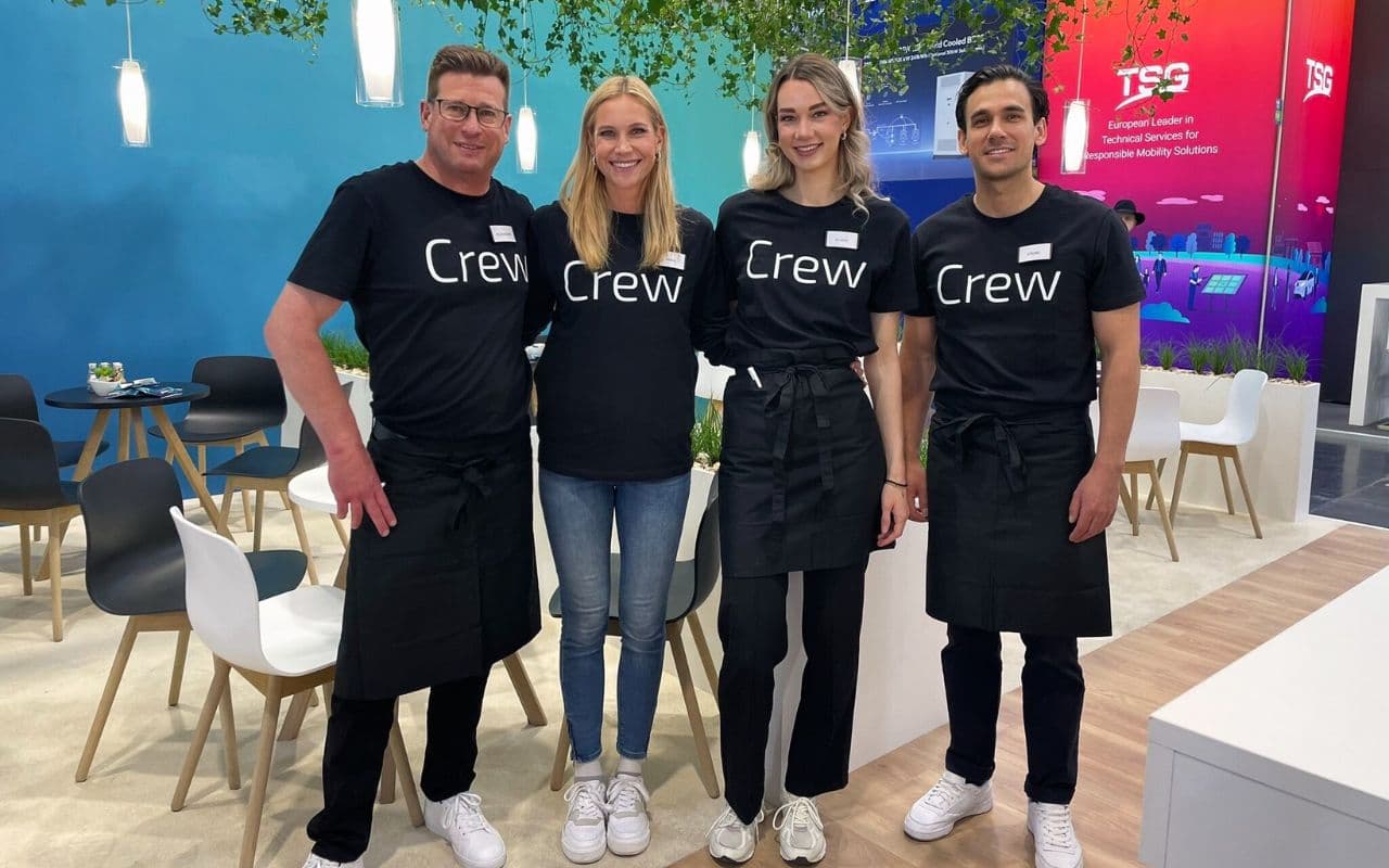 Four-person trade fair crew in black crew shirts at an exhibition stand